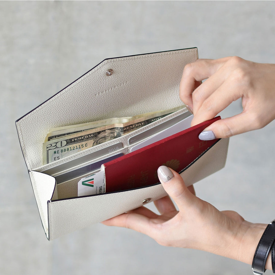 Person opens a Noblessa Envelope leather wallet and sorts their cards.