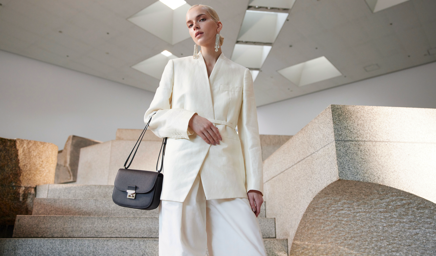 Elegant woman with leather handbag represents a sustainable capsule wardrobe.