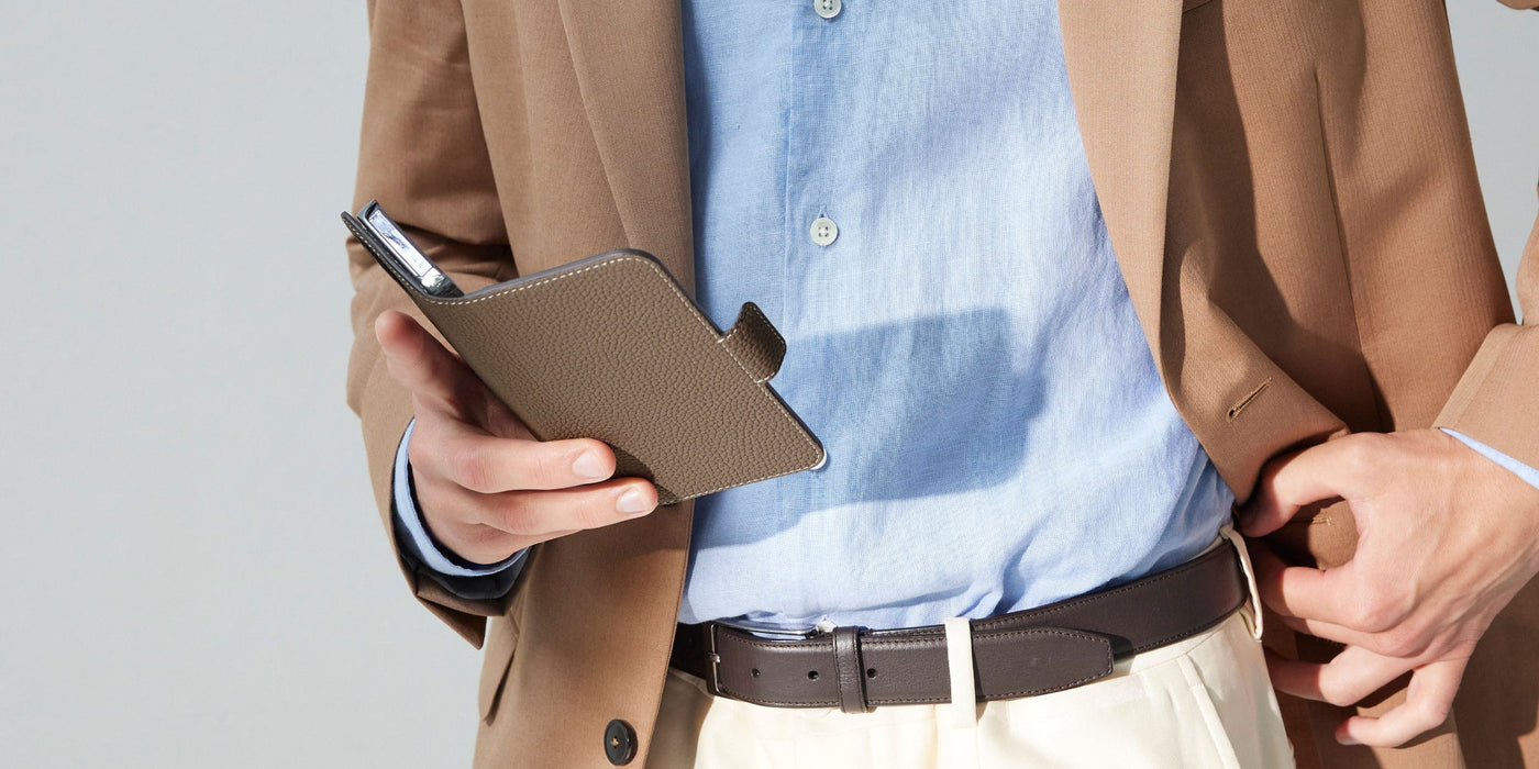 Businessman holds his iPhone 16, protected by a high-quality leather case with magnetic closure for extra protection.